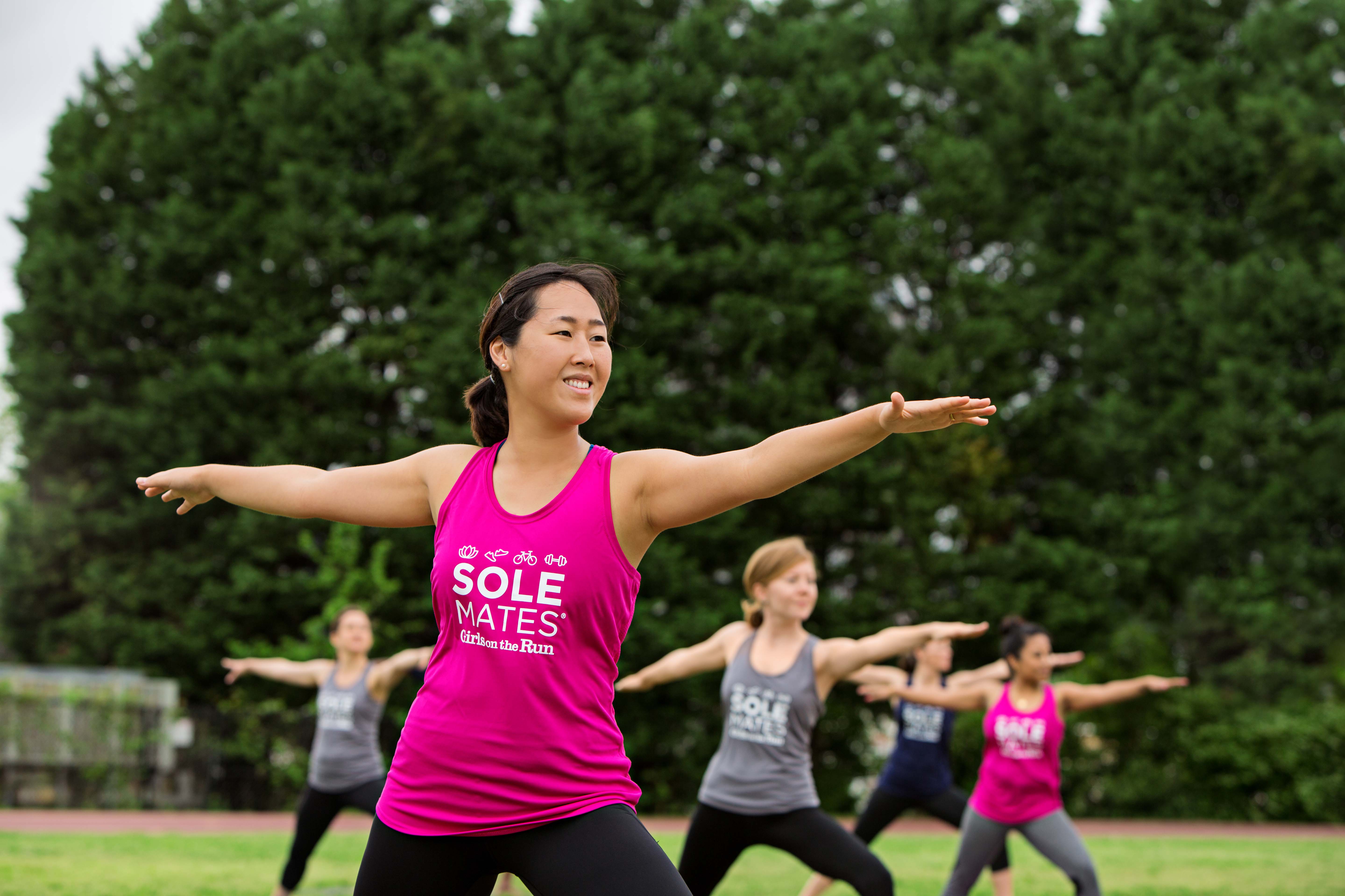 Solemates participant smiles while performing yoga pose outdoors